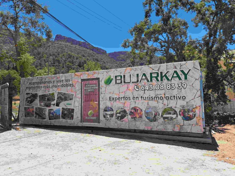 Lona impresa de gran formato instalada en caseta exterior para empresa de turismo activo con graficos e imagenes promocionales.