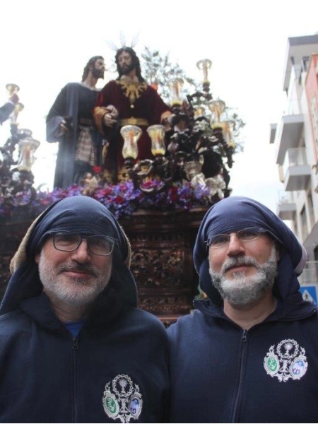 Cofrades con sudaderas personalizadas frente al Cristo del Amor durante una procesión en Jaén